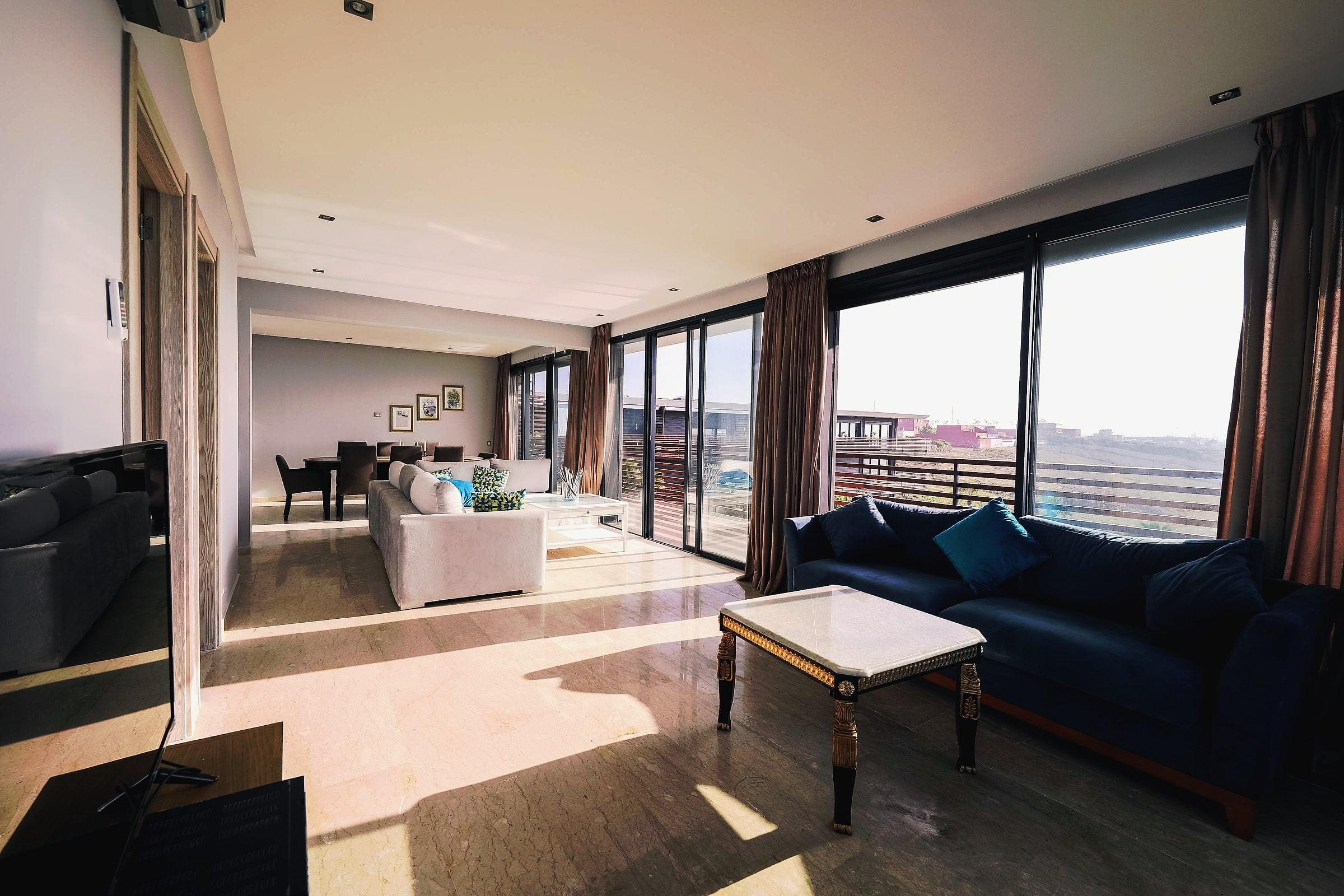 A bright living room with a sofa and floor-to-ceiling windows onto a balcony.