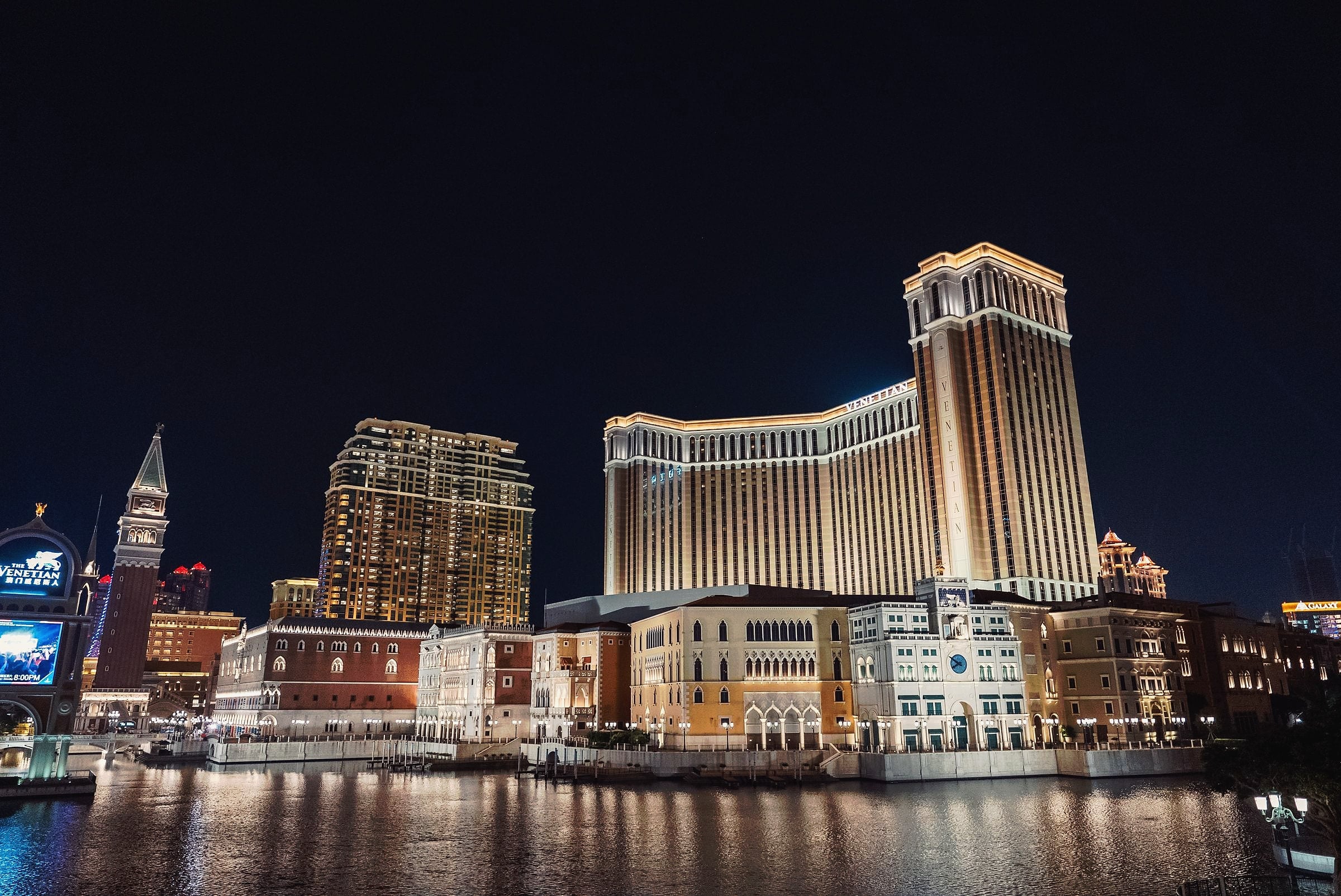 Resort towers in Cotai reflected in the water at night.
